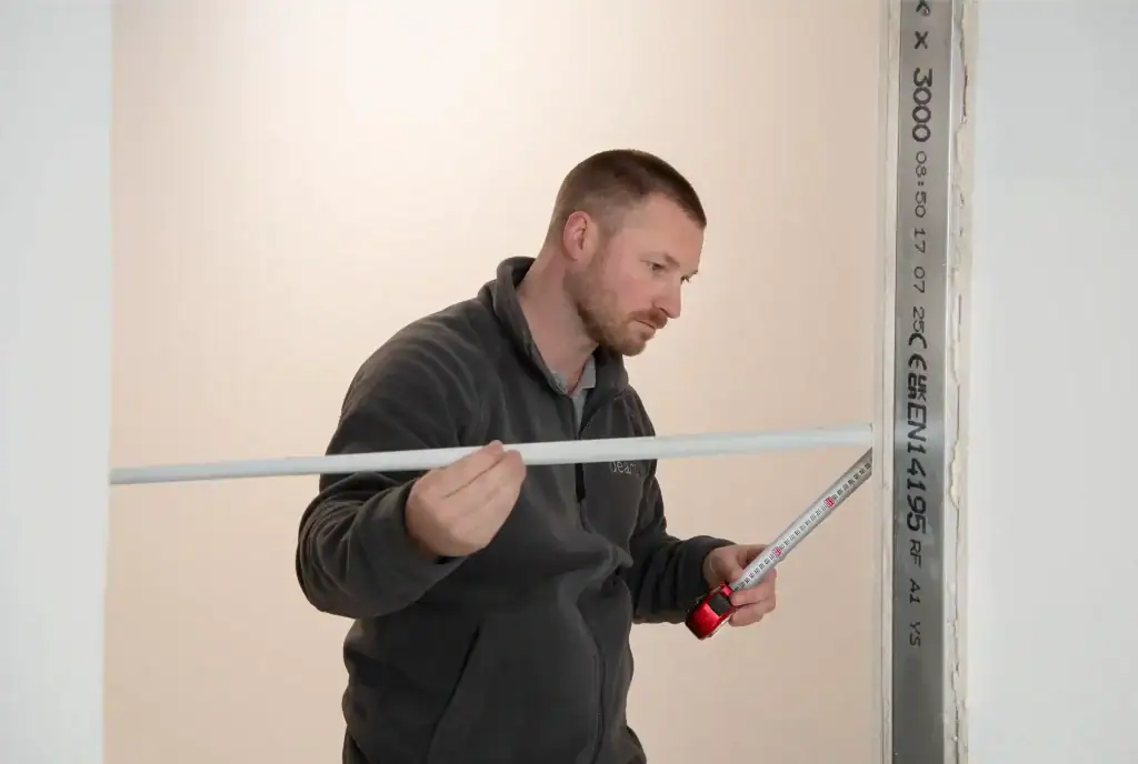 Man measuring wall for Deanta internal door fitting.