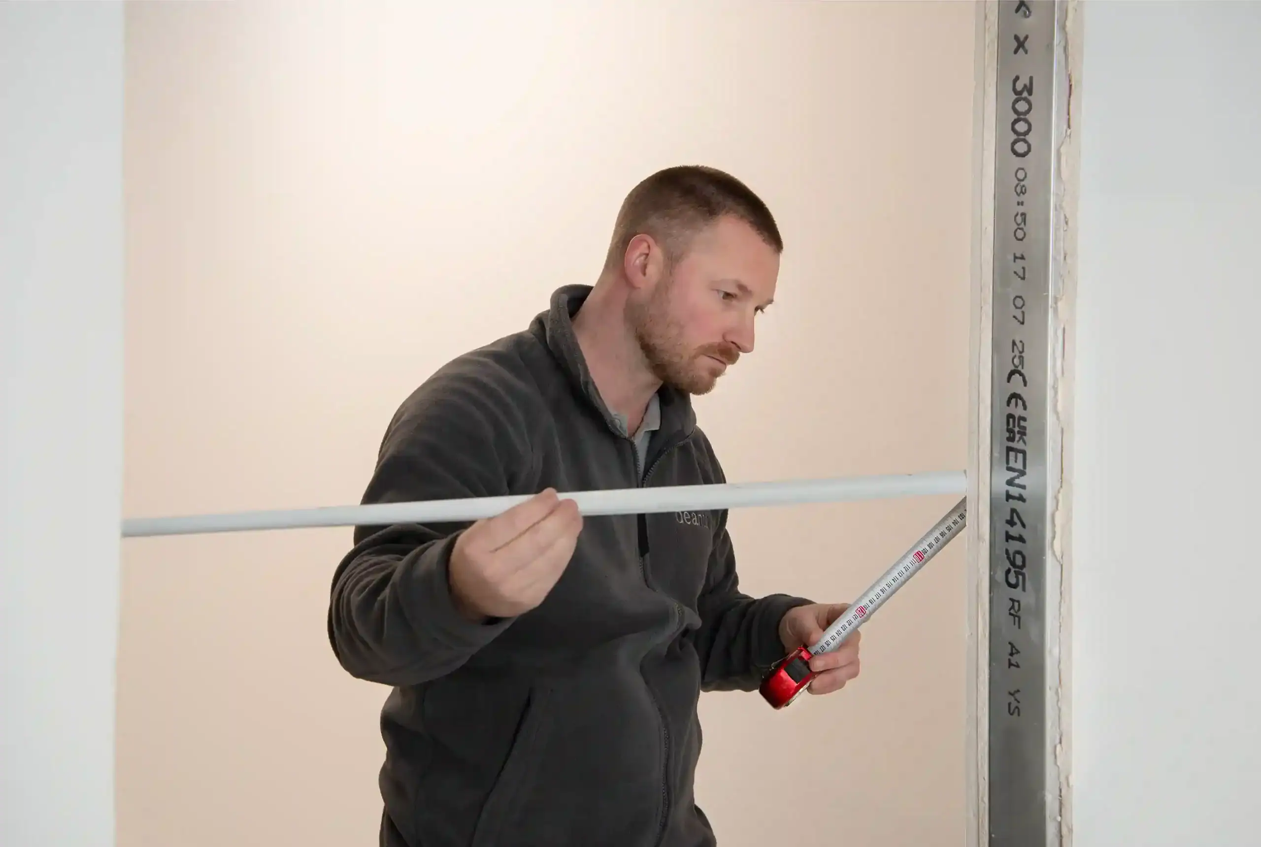 Man measuring wall for Deanta internal door fitting.